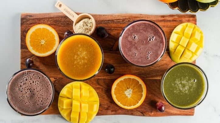 Frisch zubereitete Smoothies mit Obst auf einem Holzbrett